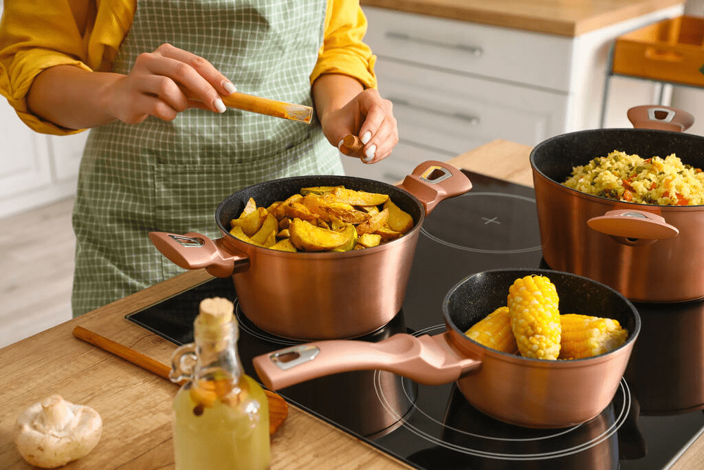 Home cook using multiple pots and pans on a stovetop in a modern kitchen