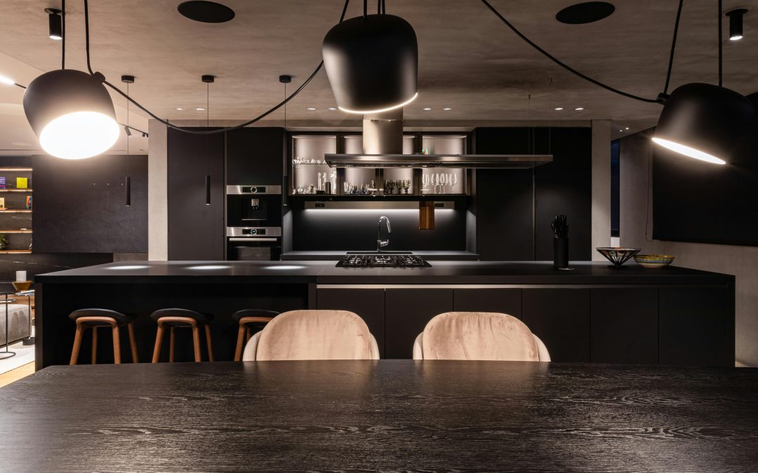 Contemporary kitchen with dark cabinetry, stone benchtop, and layered lighting setup.